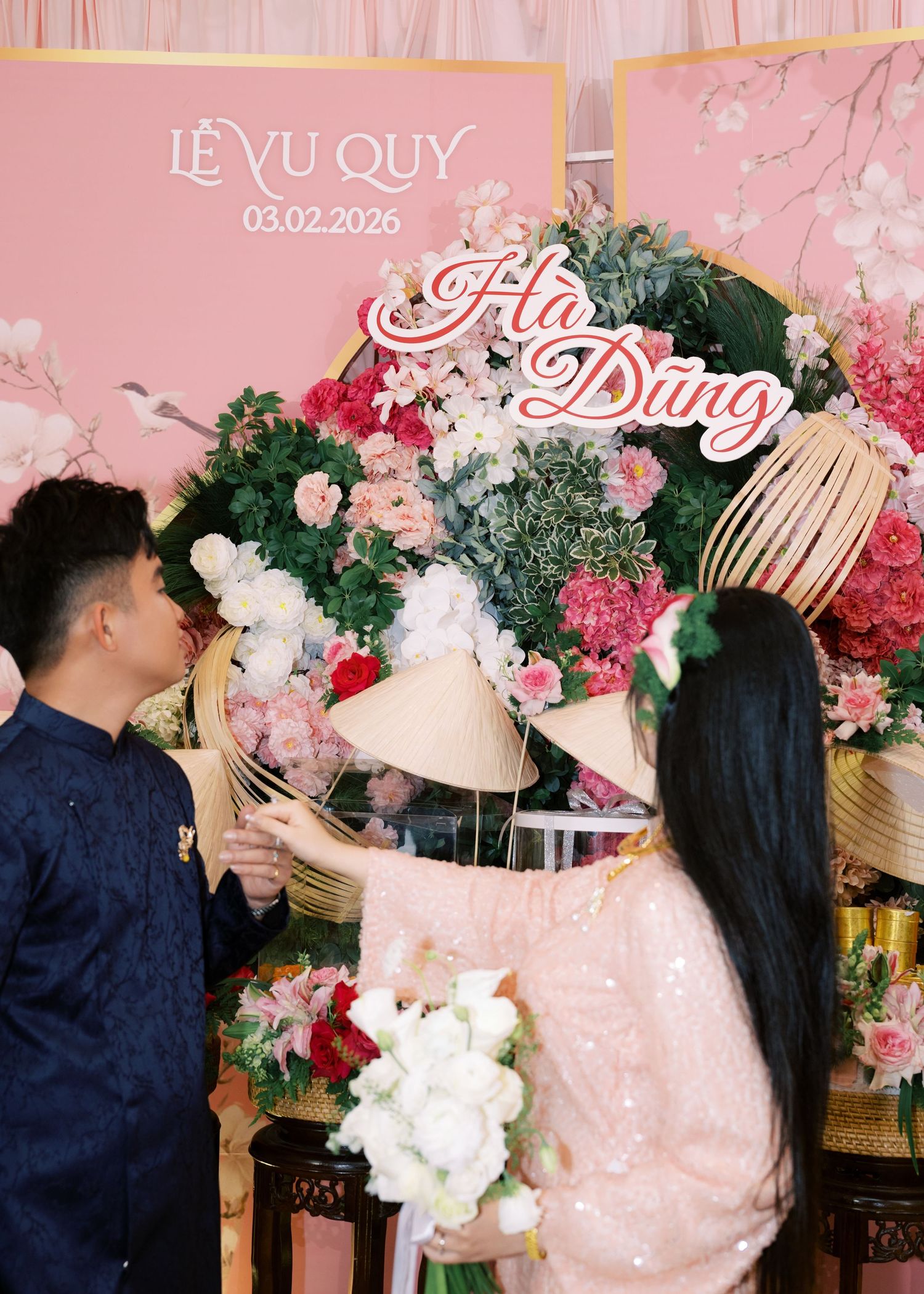 Vietnamese couple at wedding backdrop reading Le Vu Quy with names Ha and Dung dated 03.02.2026.
