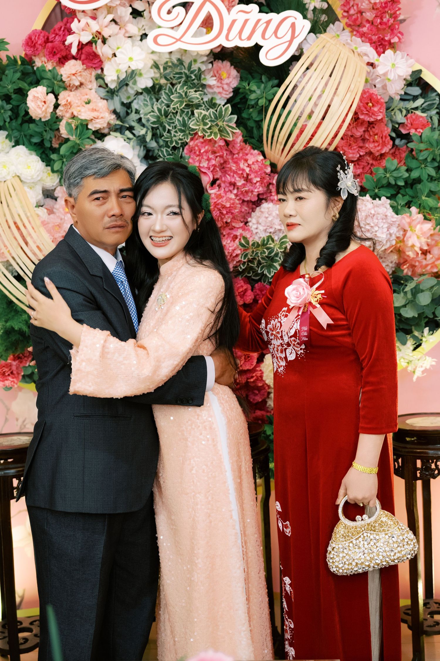 Vietnamese bride in pink ao dai embracing family members at traditional engagement ceremony.