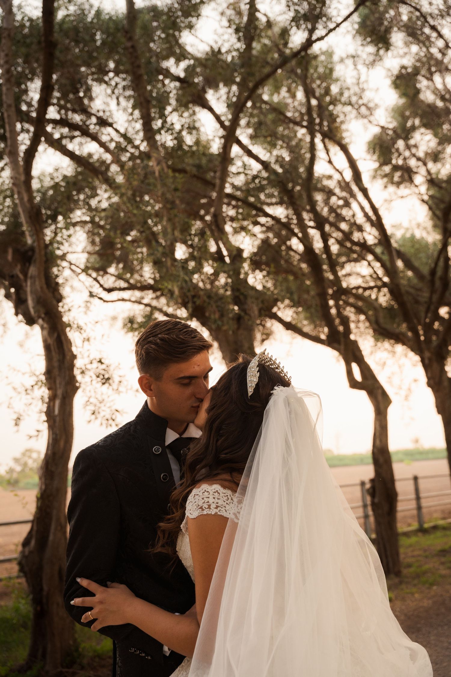 Gli sposi si baciano all'aperto, abbracciati sotto gli alberi durante il matrimonio.