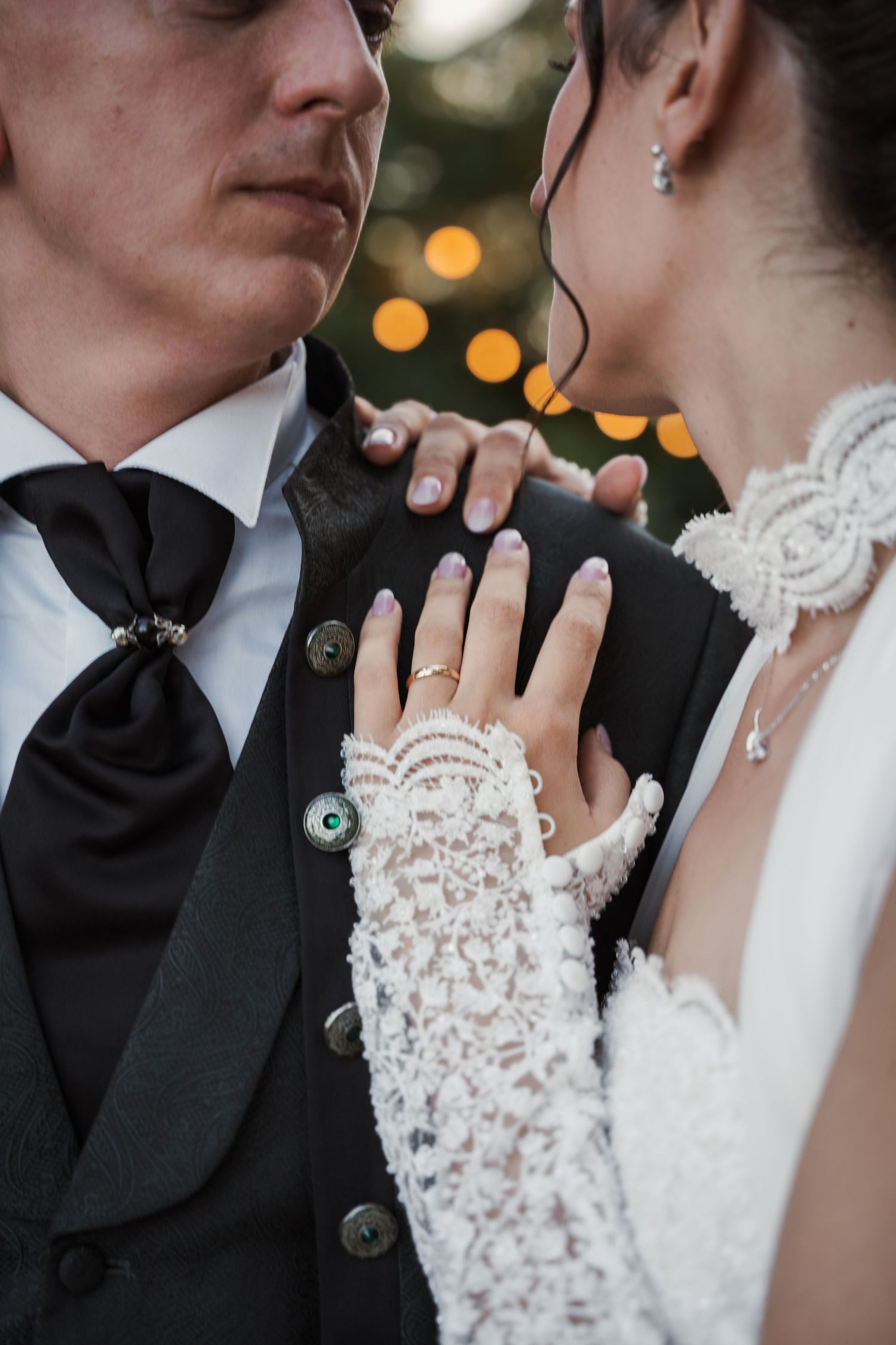 Dettaglio della sposa che appoggia la mano sullo sposo, con la fede in primo piano.