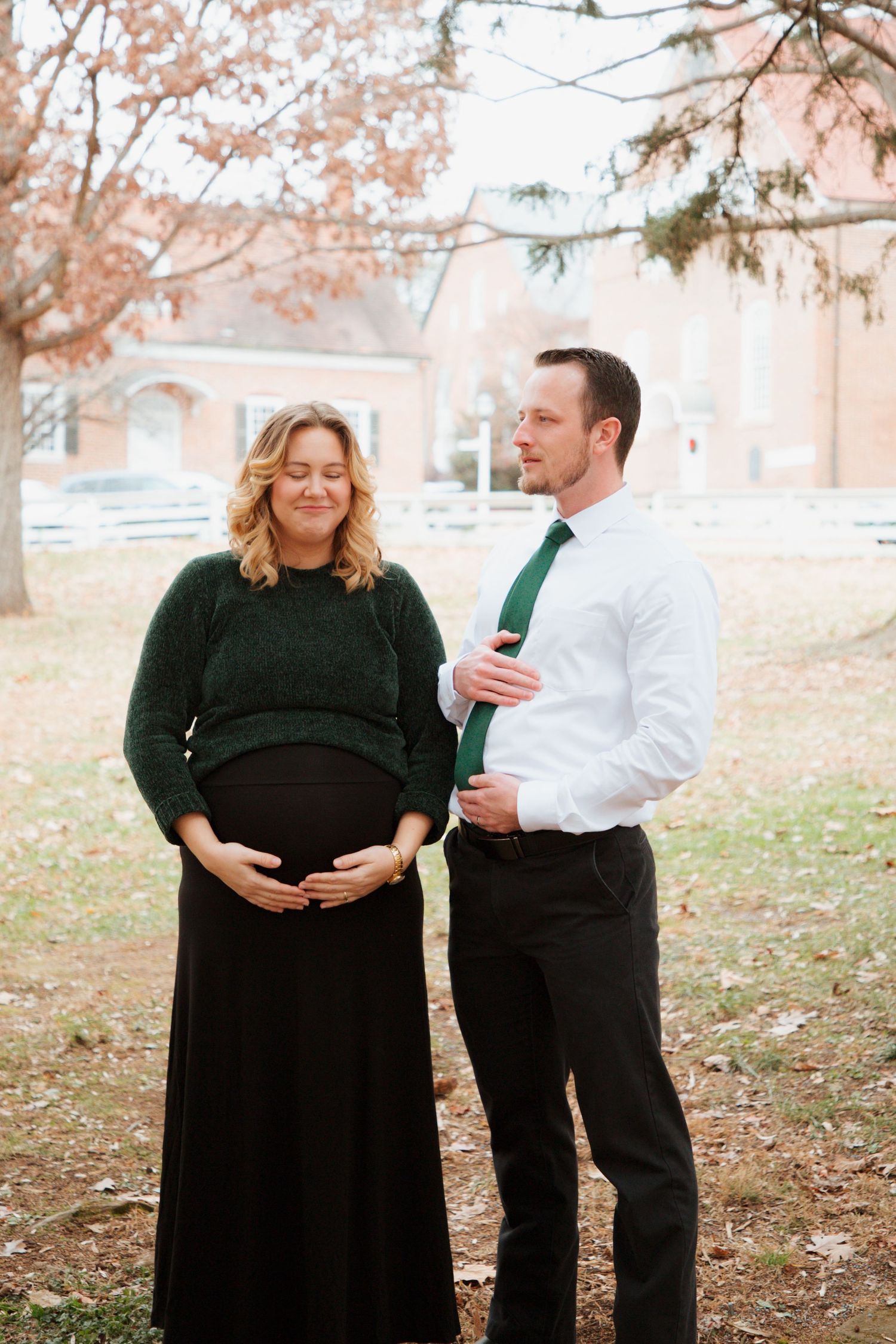 Pregnant woman and husband sharing tender moment together in autumn outdoor setting.
