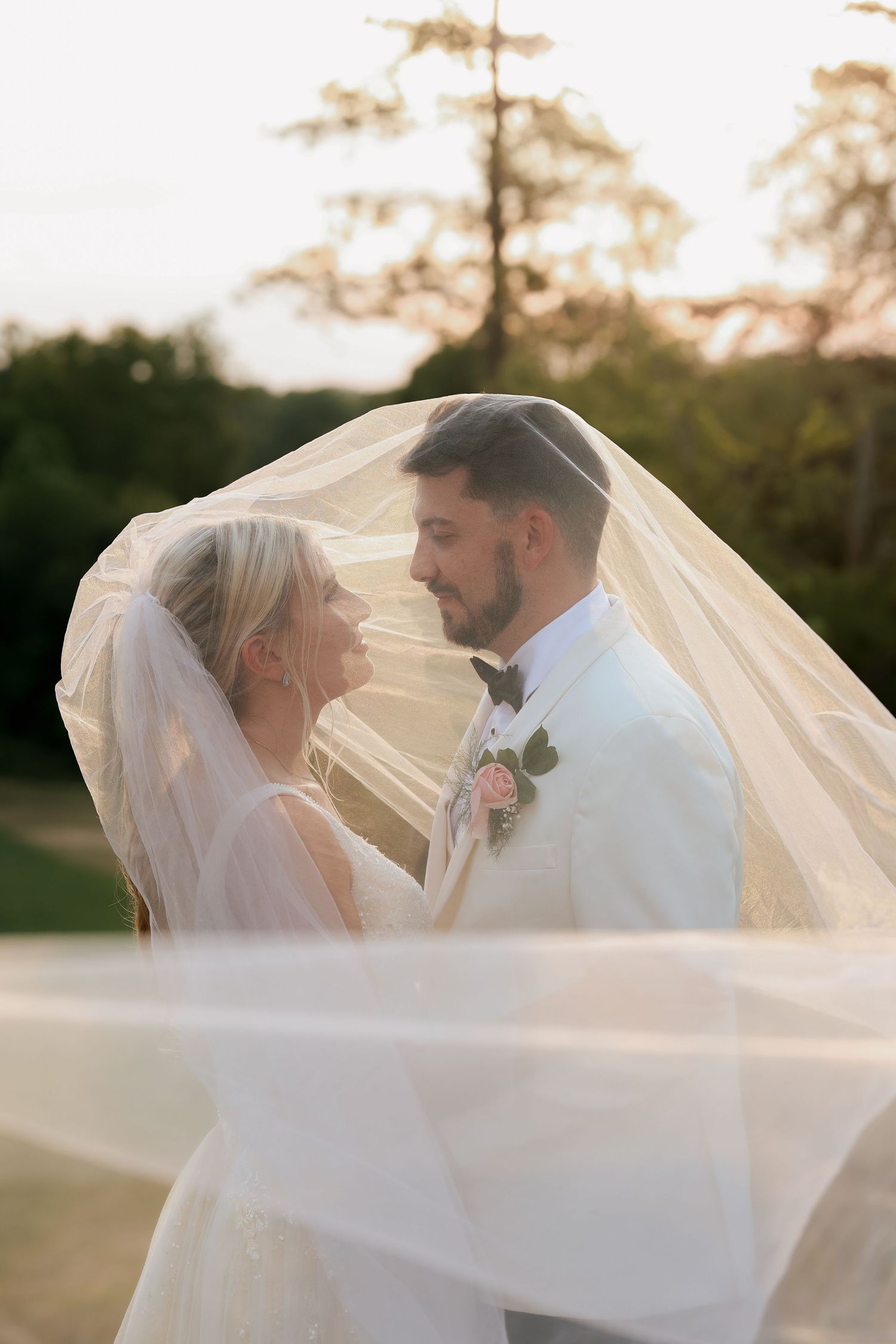 Romantic wedding portrait of bride and groom gazing at each other beneath a flowing bridal veil.