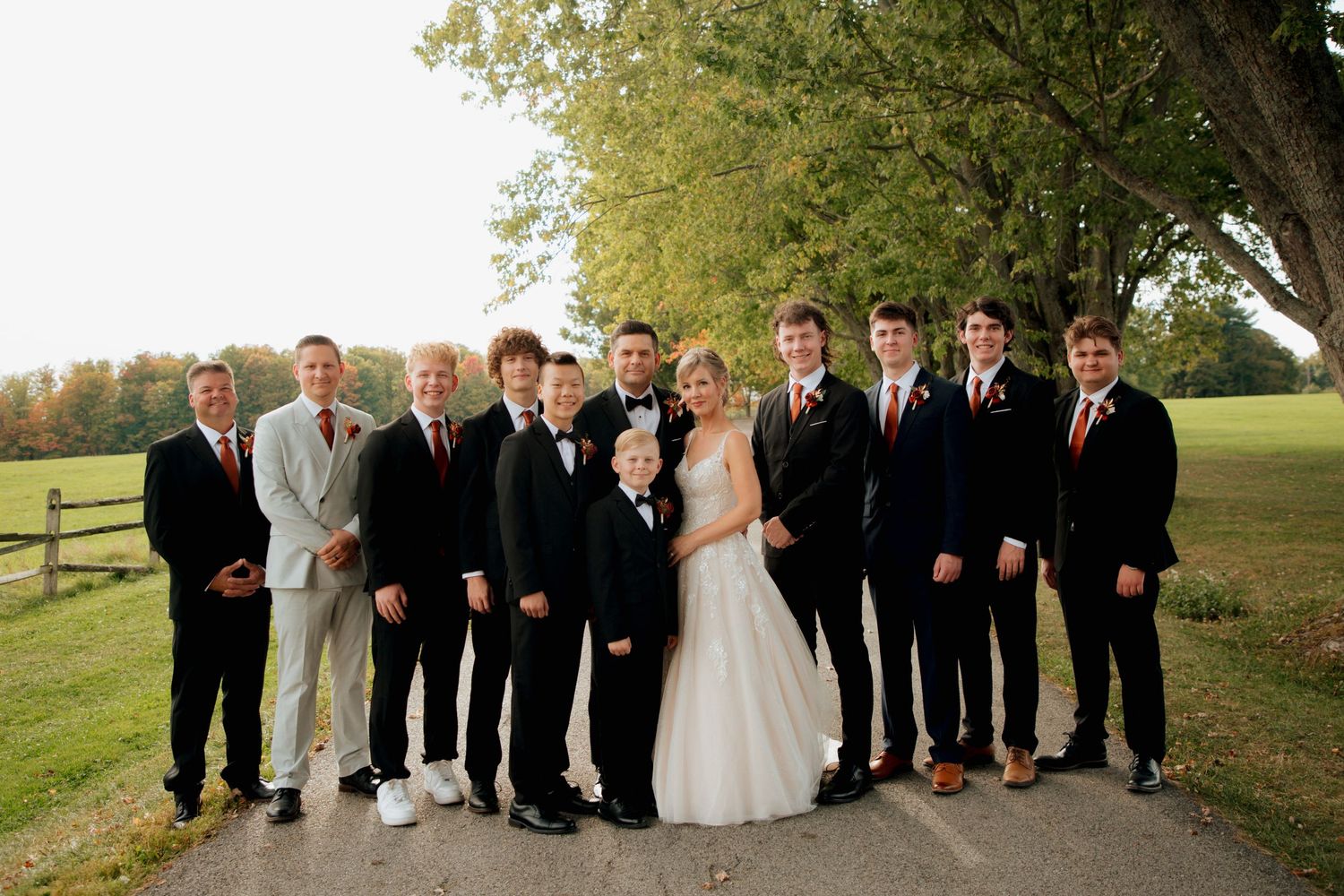 Groom with groomsmen posing formally on a scenic outdoor path.