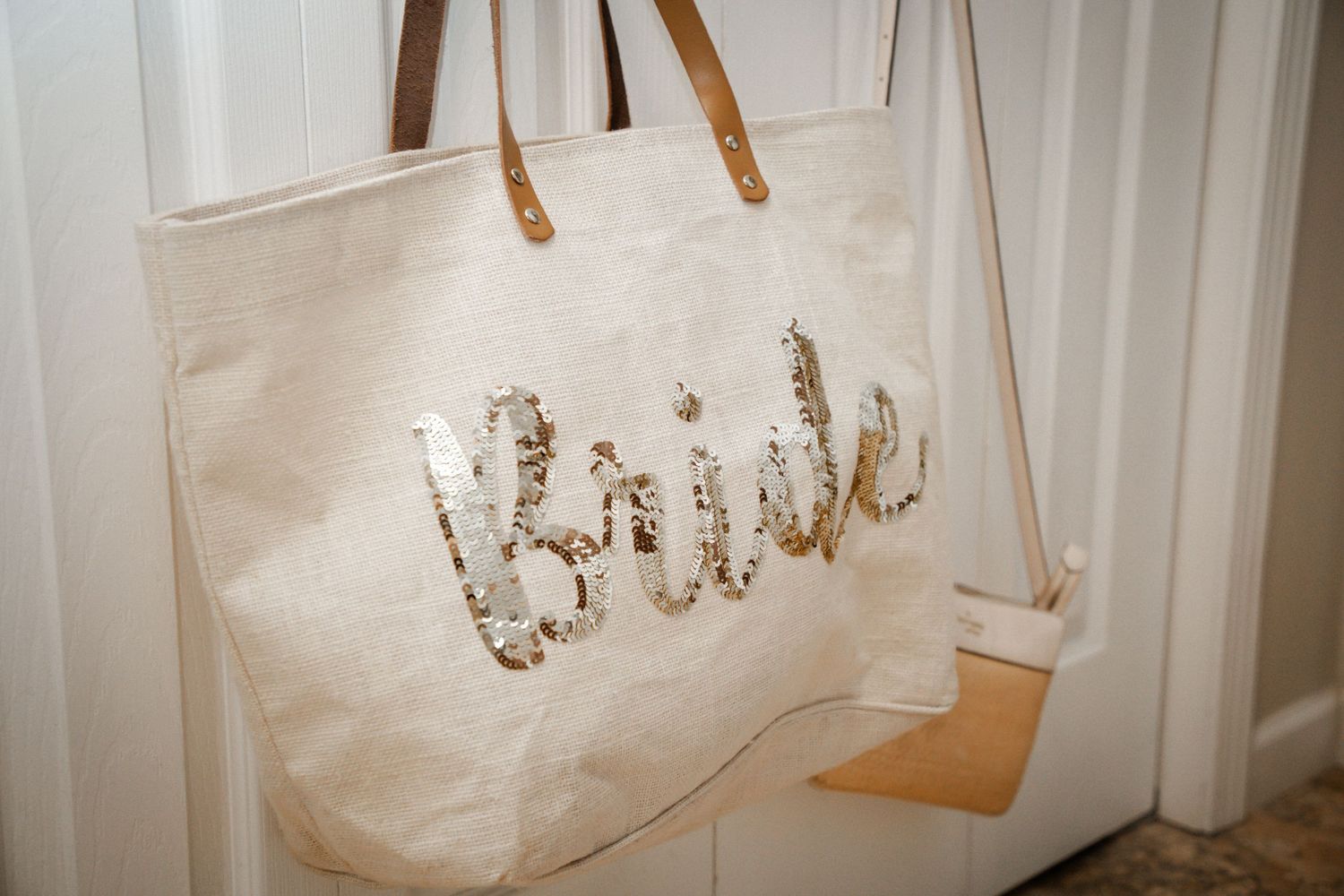 Canvas tote bag with gold sequin Bride lettering hanging on a door handle.