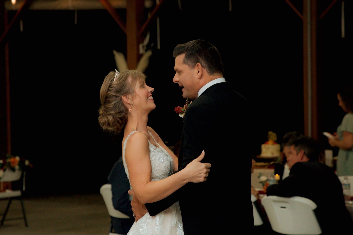 Smiling bride in tiara and groom share a joyful first dance at their wedding reception.