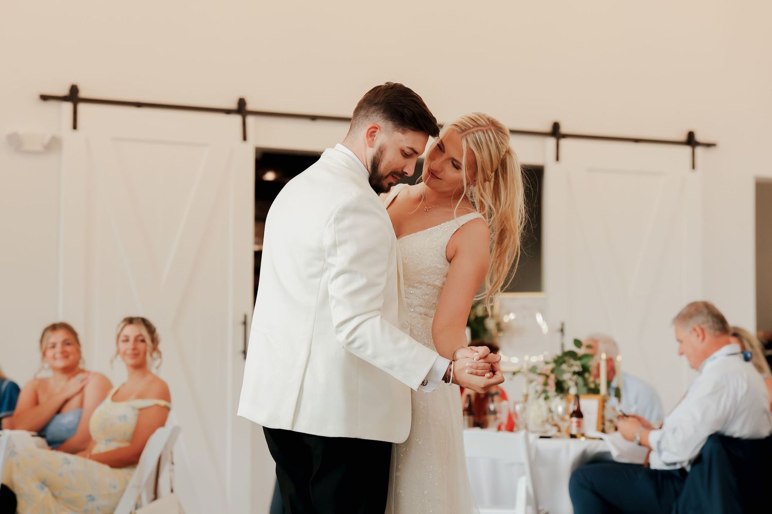 Bride and groom share romantic first dance at elegant wedding reception with floral decor.