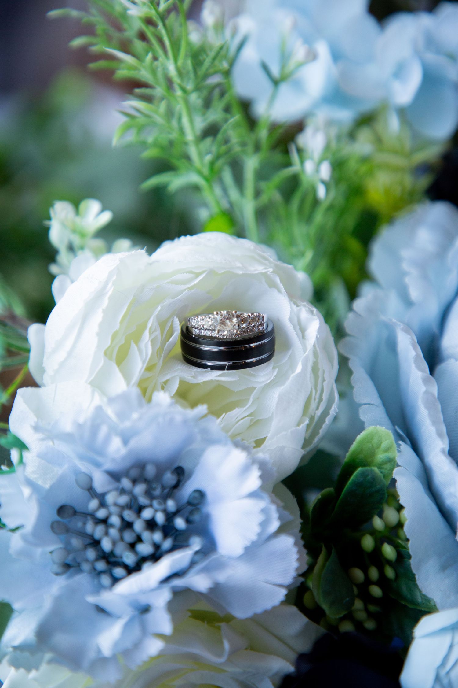 Wedding rings nestled inside a white ranunculus bloom in a blue and white floral bouquet.