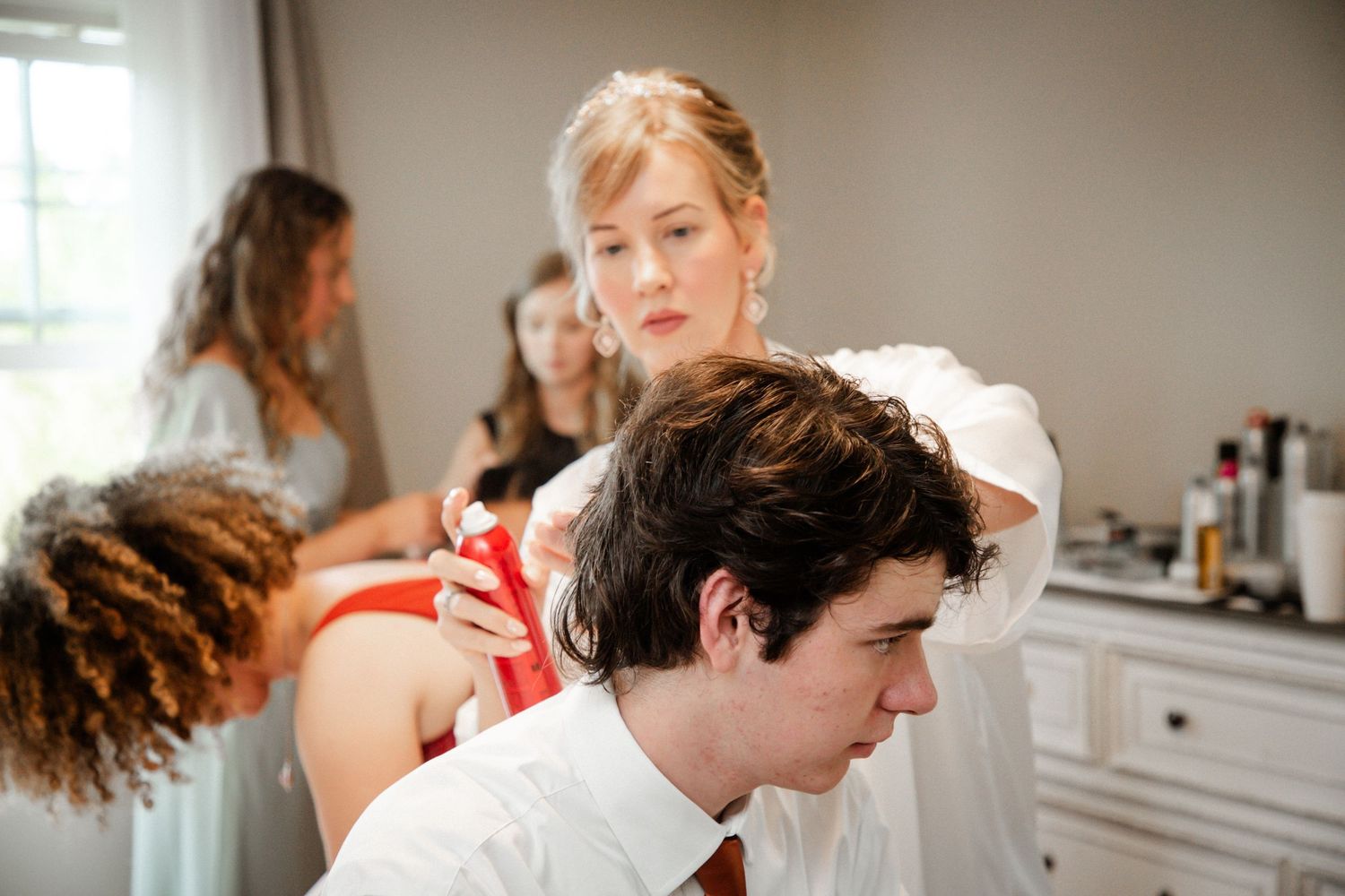 Bridesmaids helping groom with tie while getting ready for wedding ceremony.
