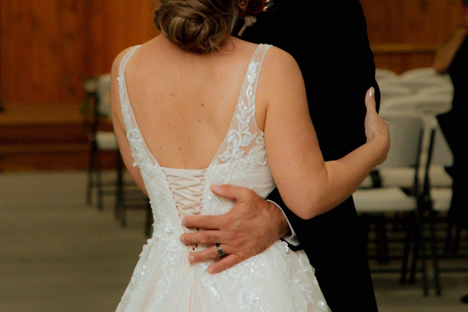Close-up of bride in lace corset wedding gown during first dance with groom at reception.
