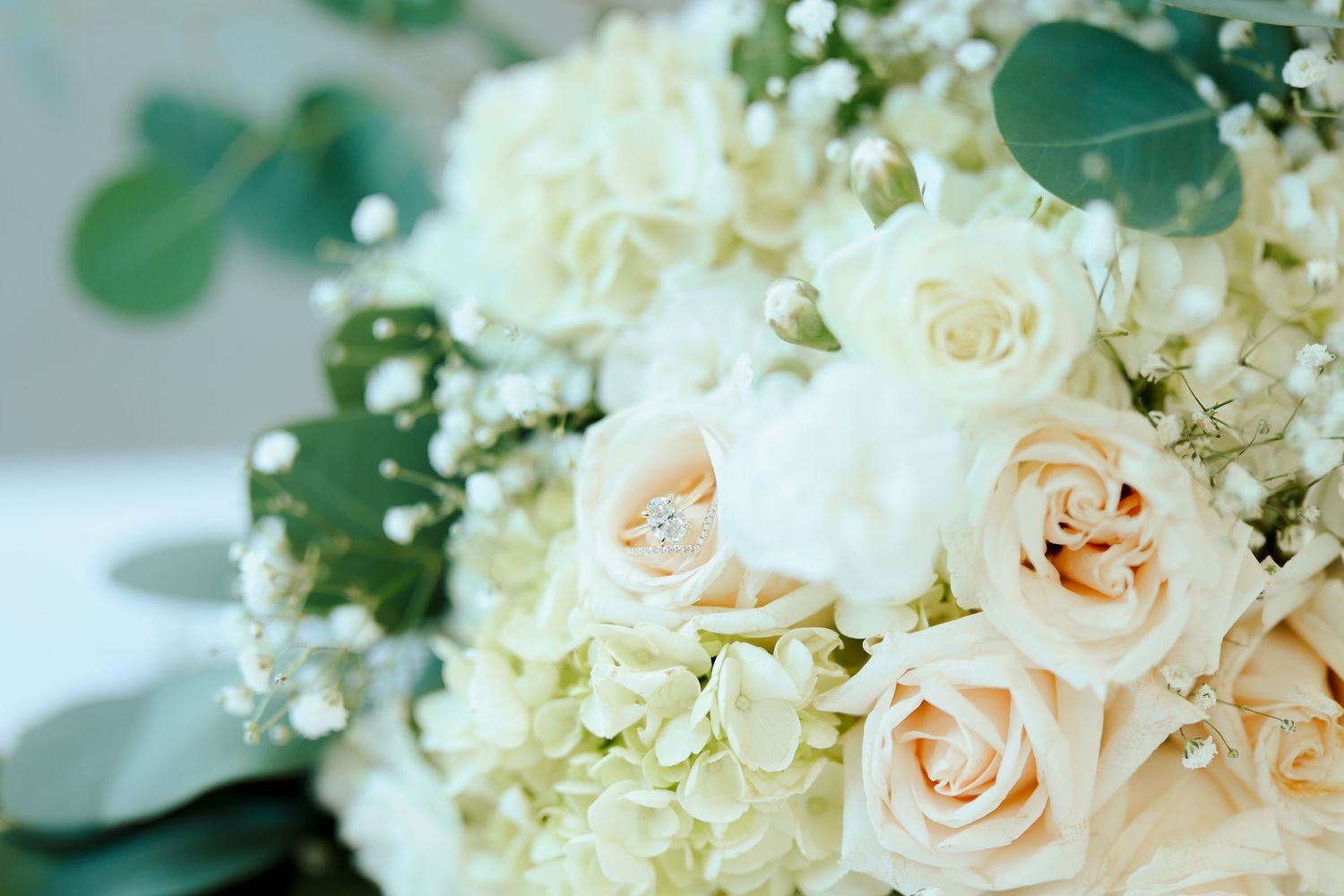 Close-up of elegant bridal bouquet with cream roses, white hydrangeas, and eucalyptus.