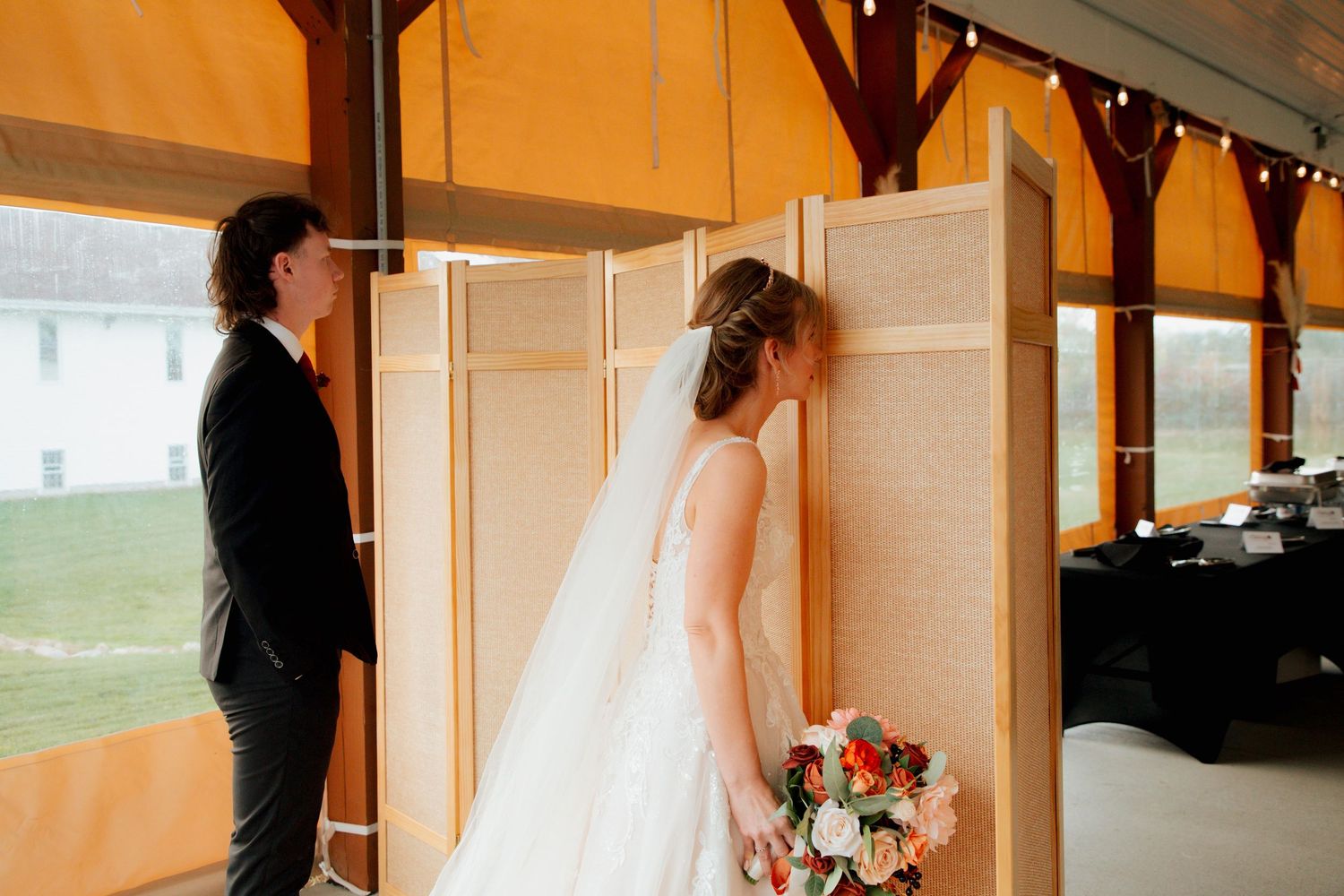 Bride and groom sharing a first look moment beside a woven room divider at a wedding venue.