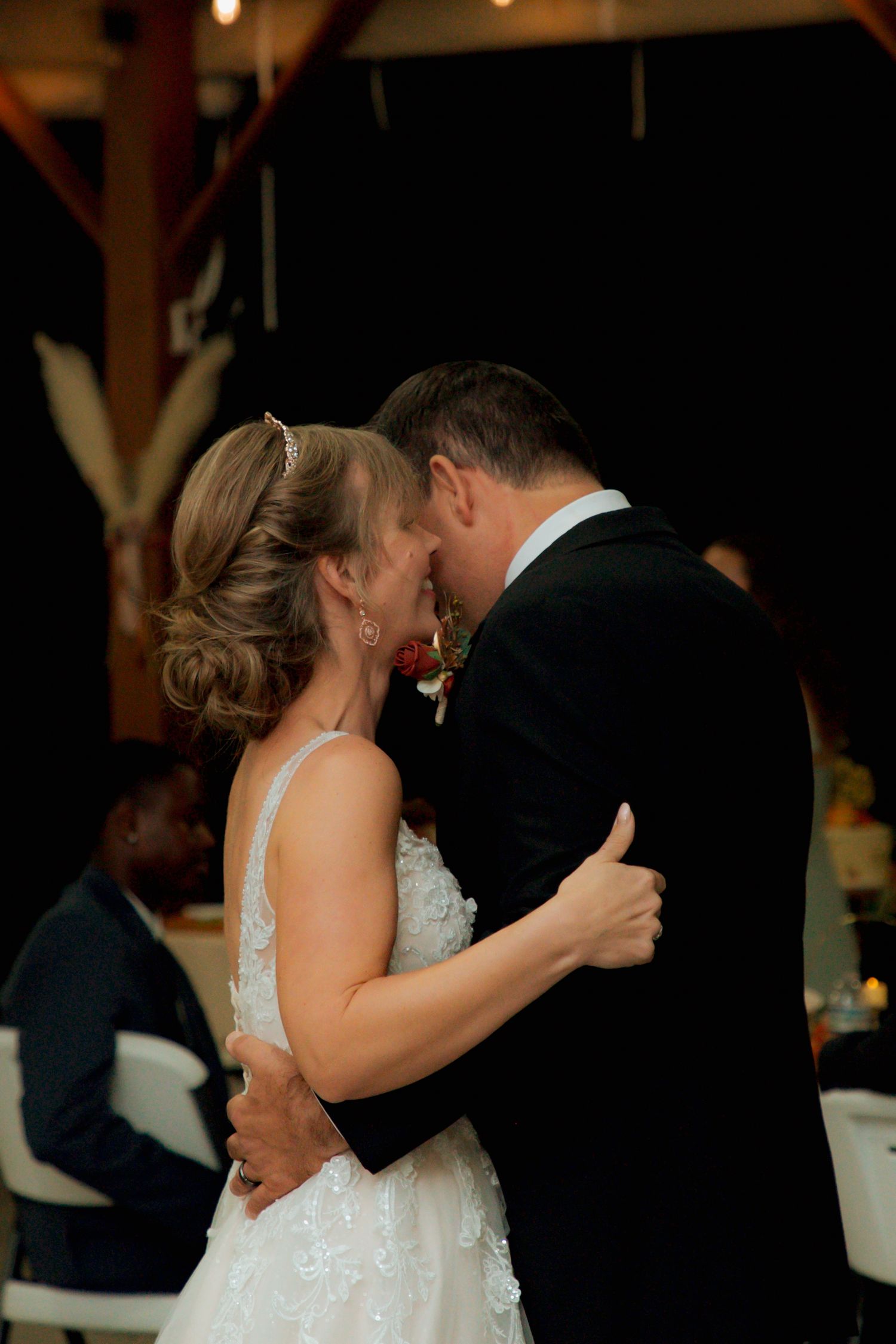 Bride and groom share a romantic close first dance embrace at their barn wedding reception.