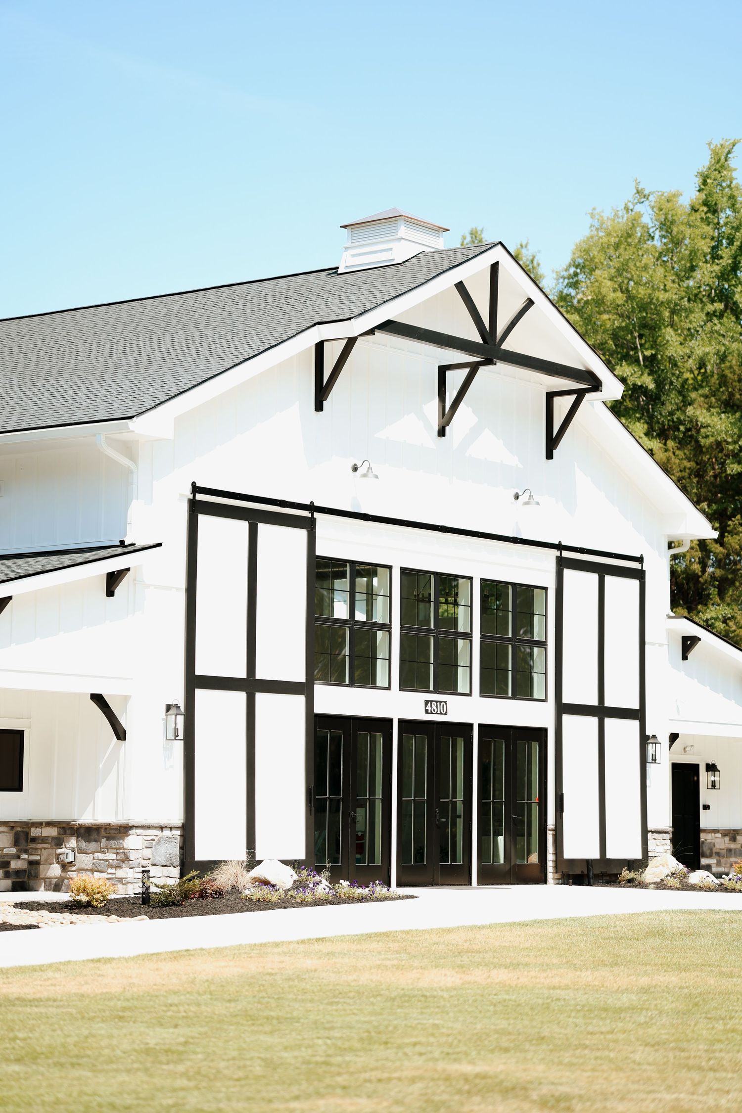 Stunning white and black Tudor-style barn wedding venue with manicured lawn on a clear day.