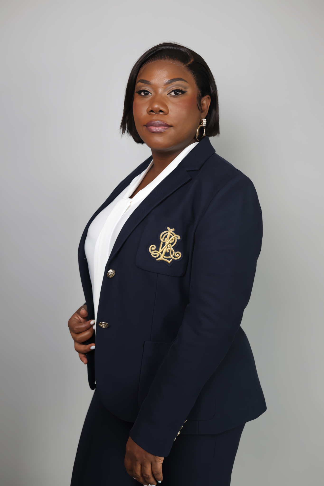 Professional woman in navy Lauren blazer with gold crest posing for a formal portrait photo.