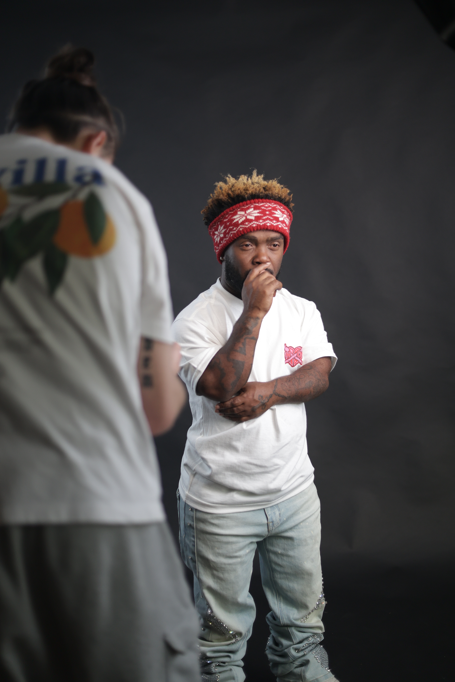 Young man with blonde tips and red bandana headband in white tee poses in studio.
