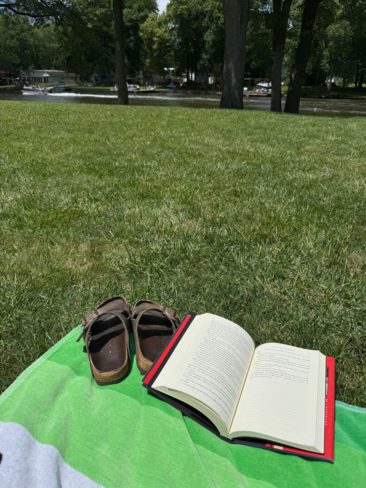 Sandals and book laid out on a towel outside.