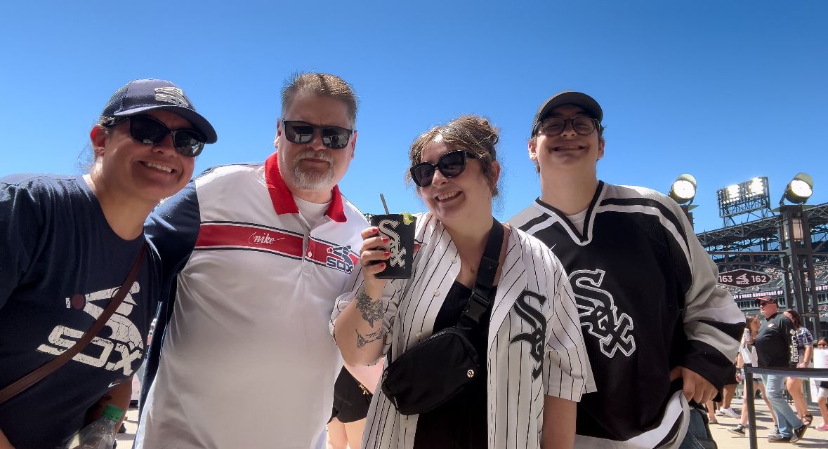 Family of four pose at Chicago White Sox game.