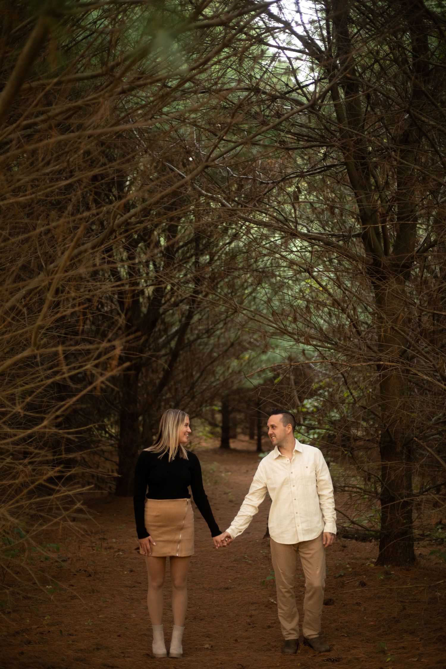 Man and woman holding hands in a forest in Michigan City.