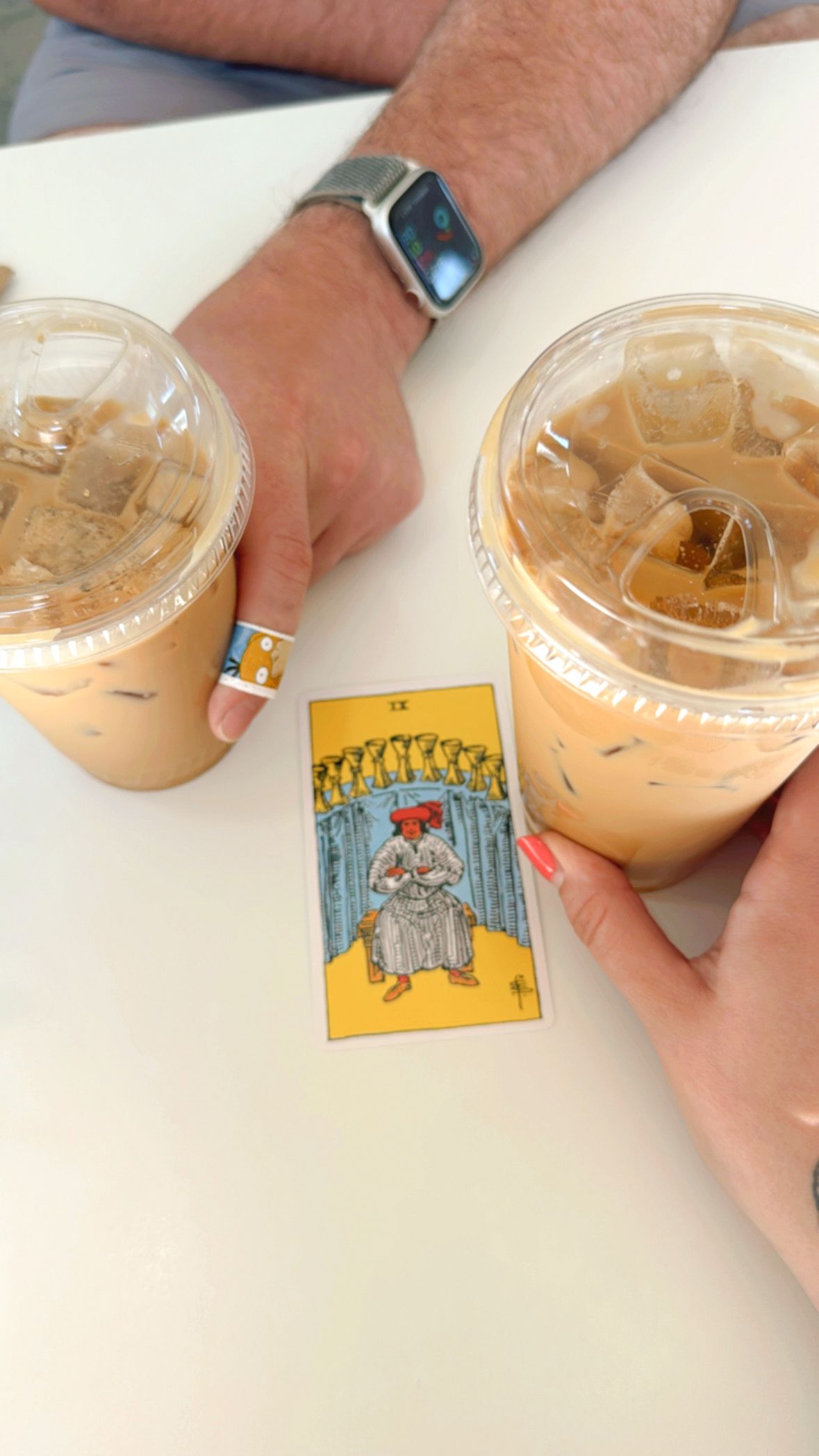two iced coffees and a tarot card on a table.