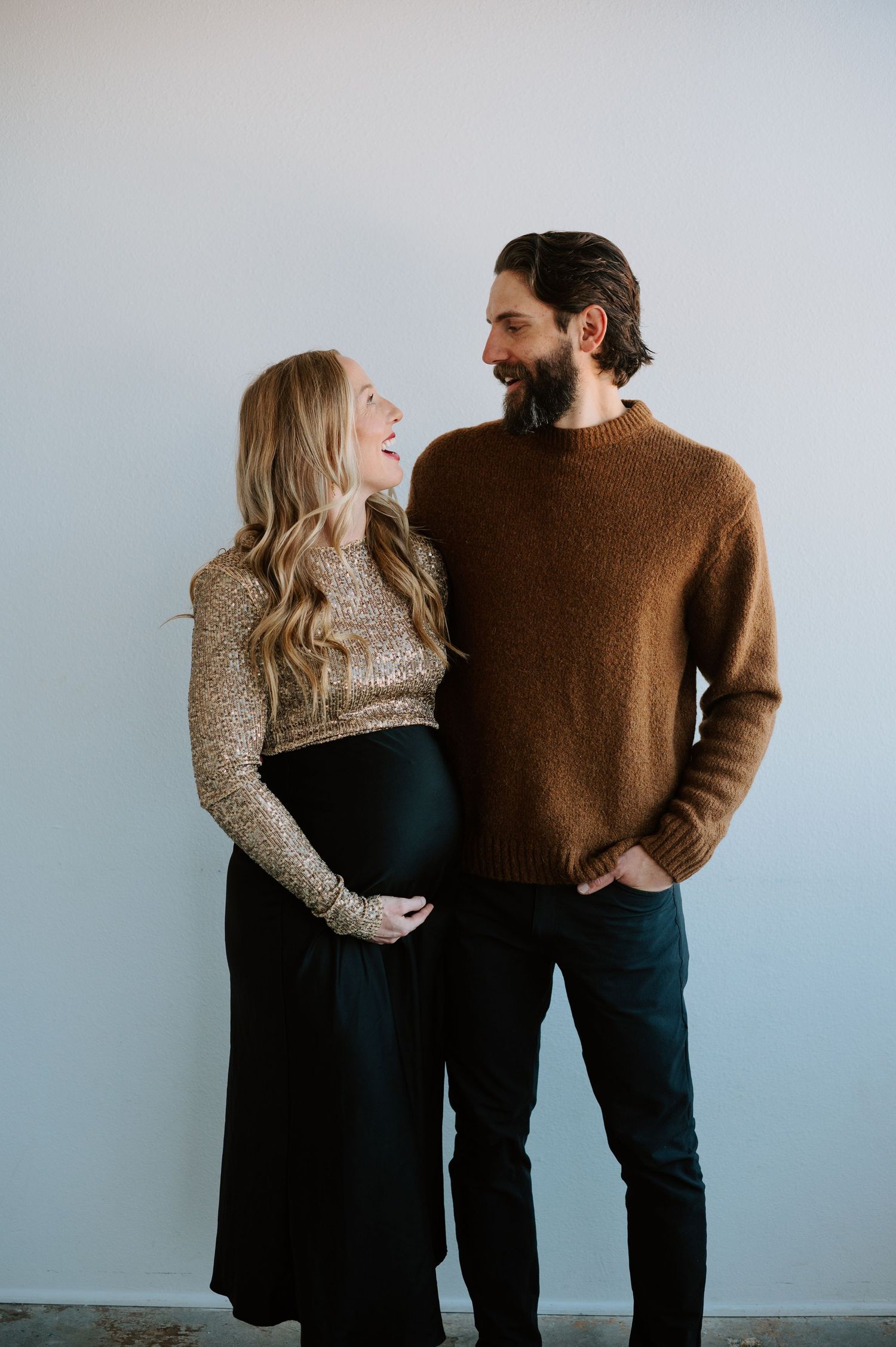 A glowing couple embraces the winter chill, their love and excitement shining through the snow as they await their little one’s arrival