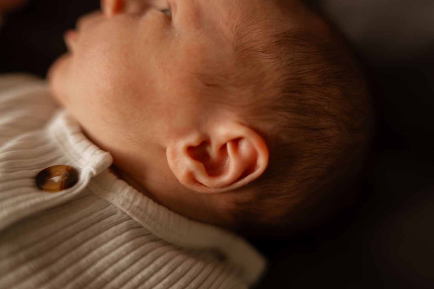 A series of close-up photos showing different angles of a sleeping baby in soft lighting.