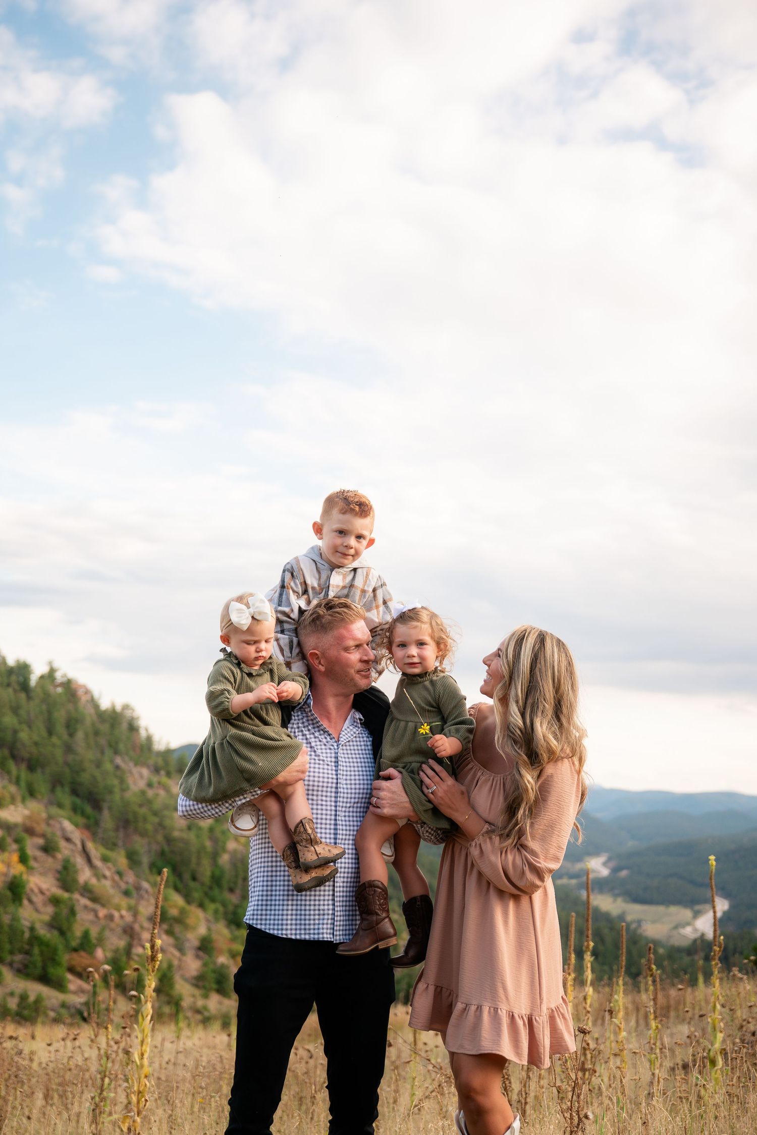 Family enjoys a tender moment together while standing on a scenic mountain overlook during golden hour.