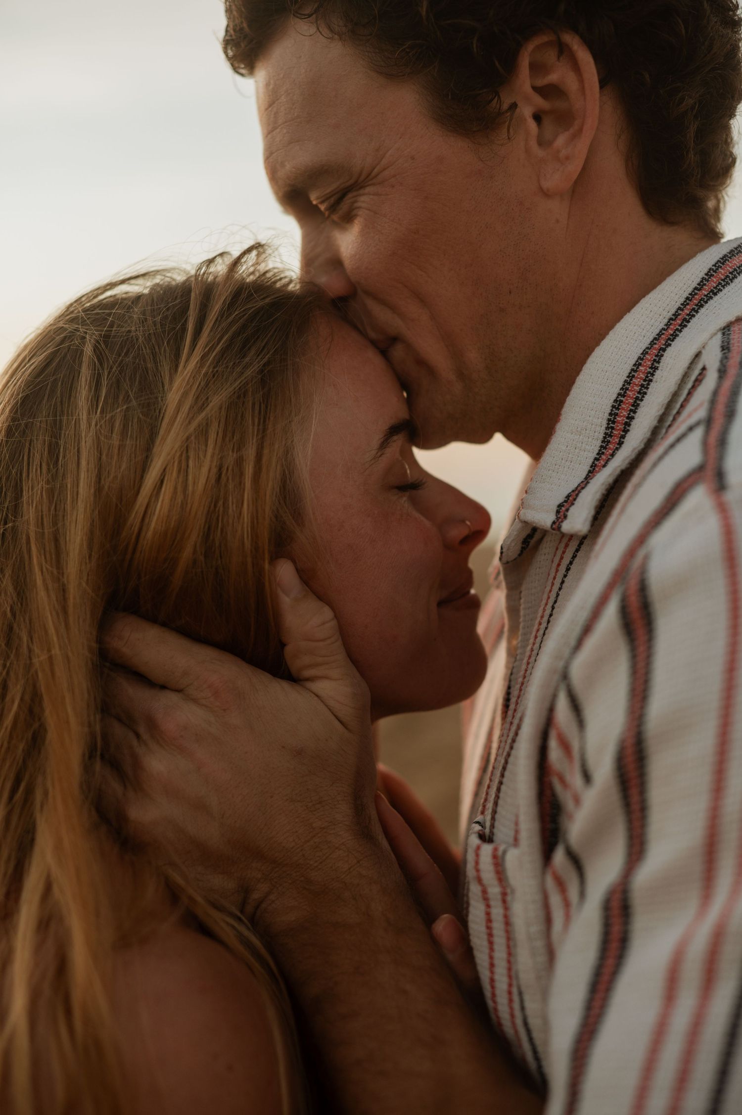 Romantic engagement photo of couple during golden hour at Newport Beach with an ocean background