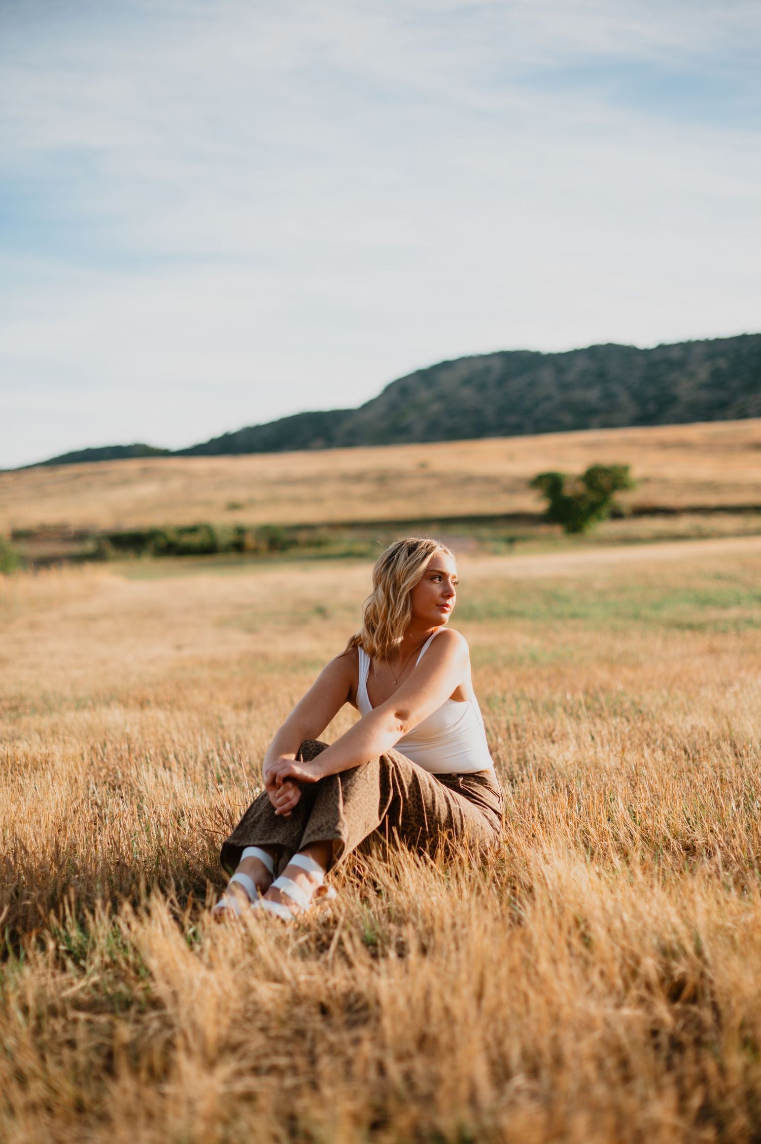 A senior girl shines in her cute outfit, with her blonde hair glowing against the scenic beauty of Littleton, Colorado—capturing her vibrant