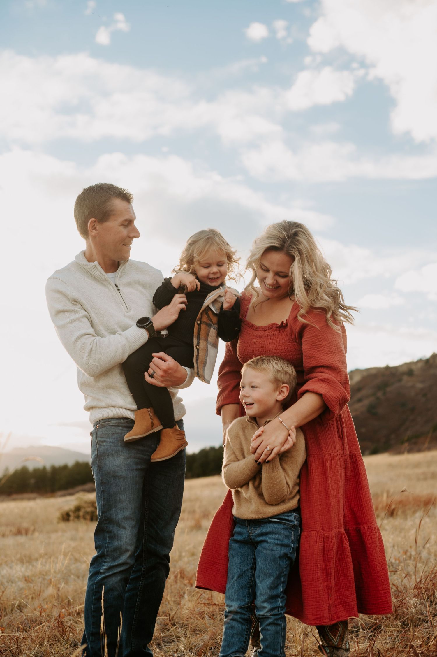 A loving family embraces golden hour in Castle Rock, Colorado, with warm sunlight highlighting their bond against a breathtaking, peaceful b