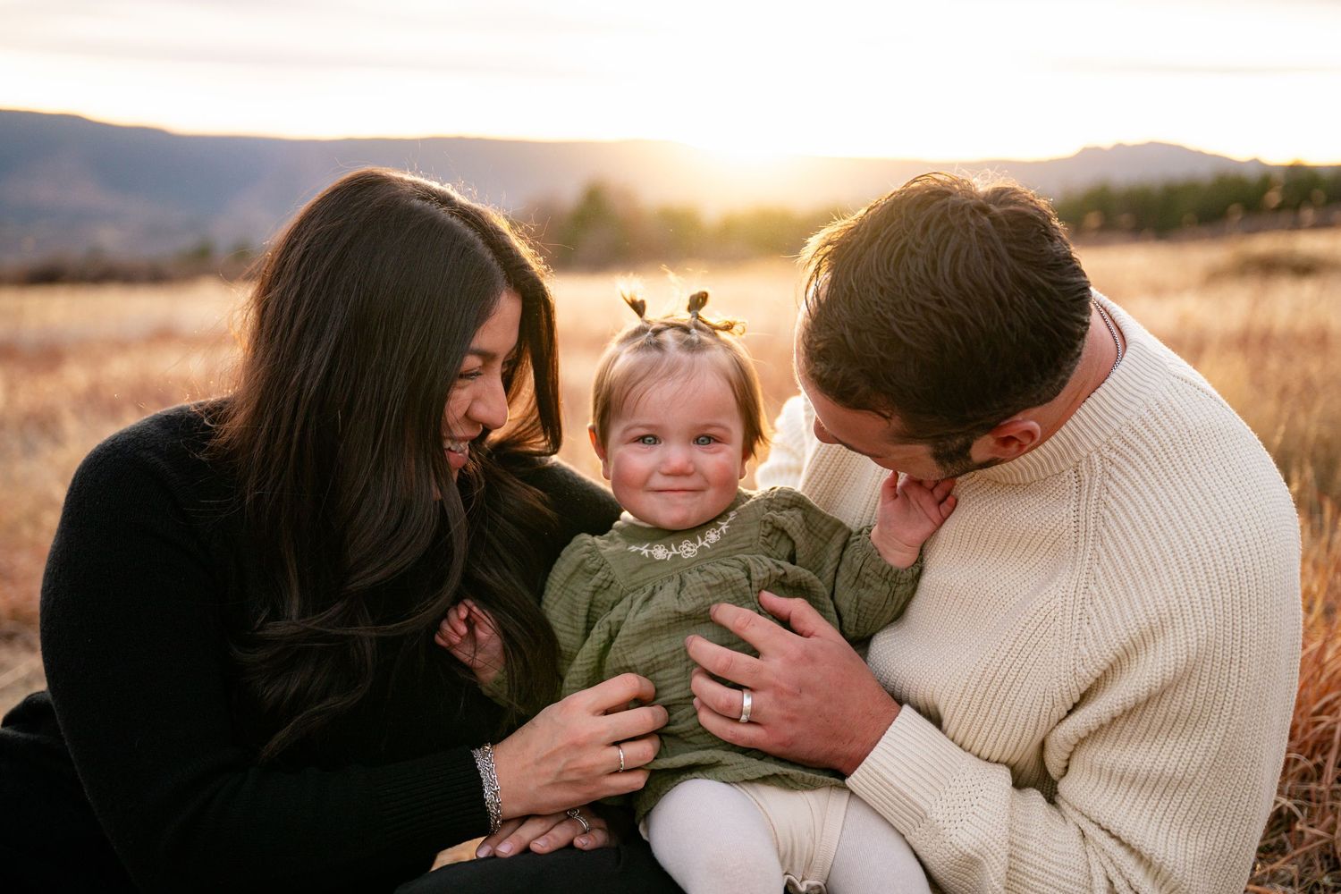 A loving family embraces and shares tender moments together during a golden sunset photo session outdoors.