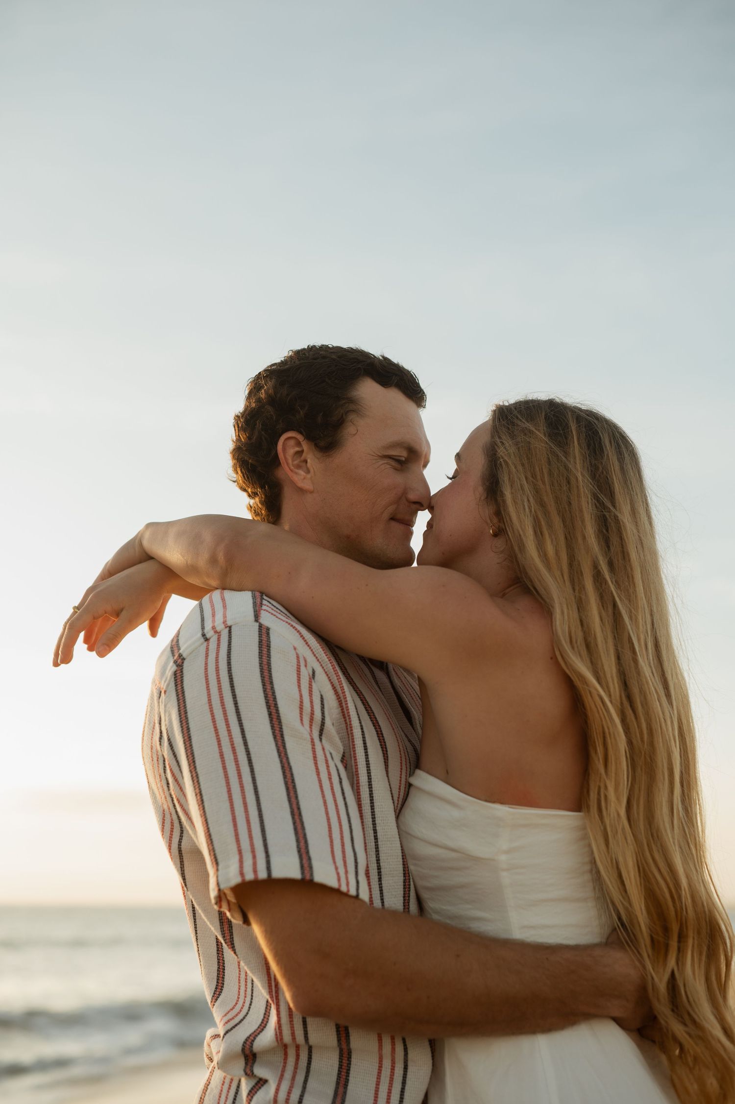 Romantic engagement photo of couple during golden hour at Newport Beach with an ocean background