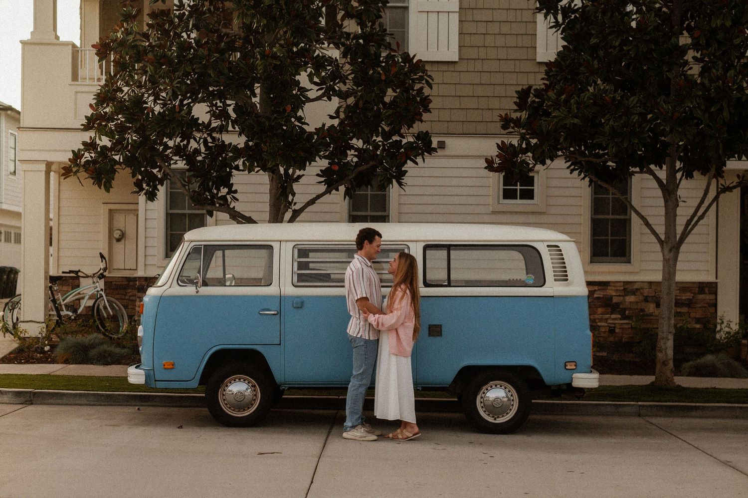 A carefree couple enjoying a sun-soaked day in Orange County, captured alongside their vintage VW van. The natural light