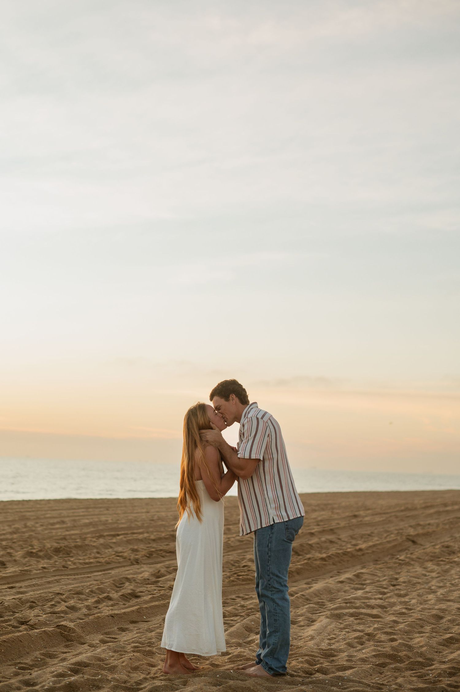 Romantic engagement photo of couple during golden hour at Newport Beach with an ocean background