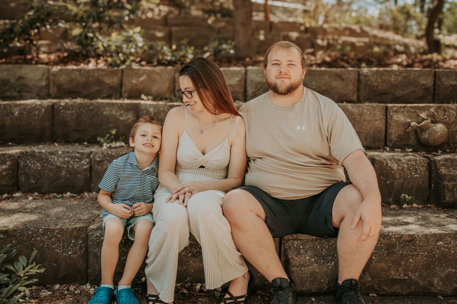 Family sitting together on rustic stone steps during an outdoor photo session at golden hour.