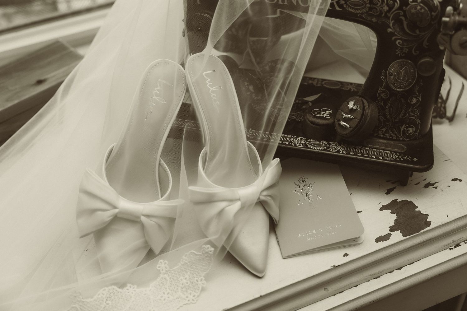 Elegant white wedding shoes with bow details rest beside vintage photographs in a sepia-toned artistic composition.