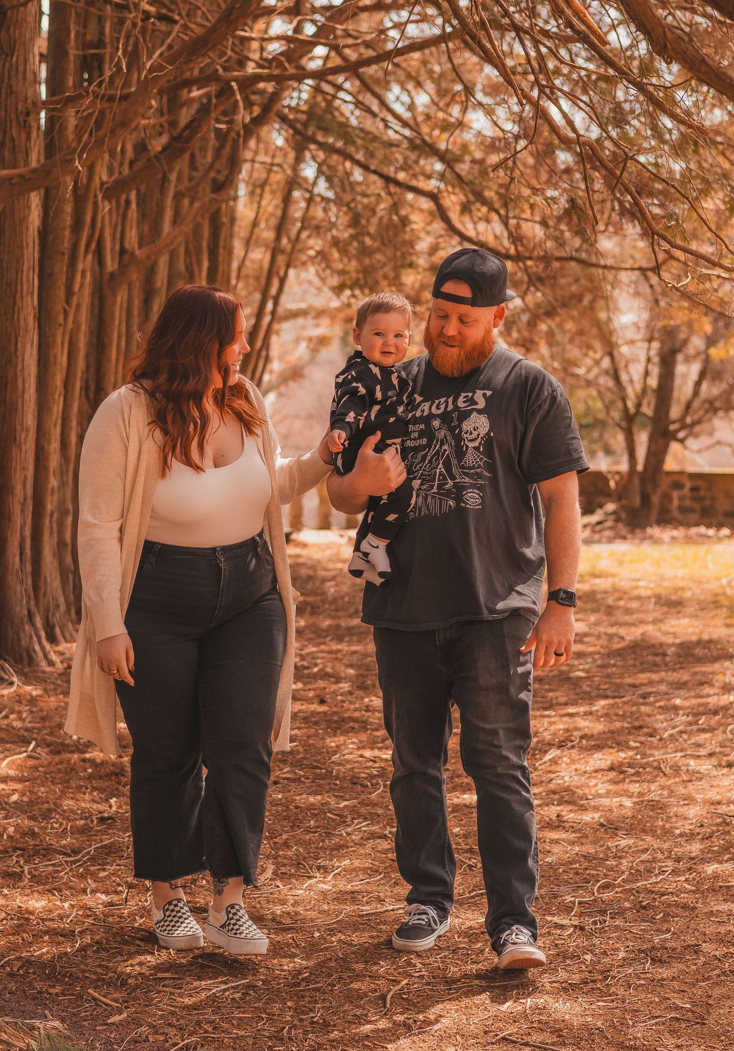 Family walks together on tree-lined autumn path.