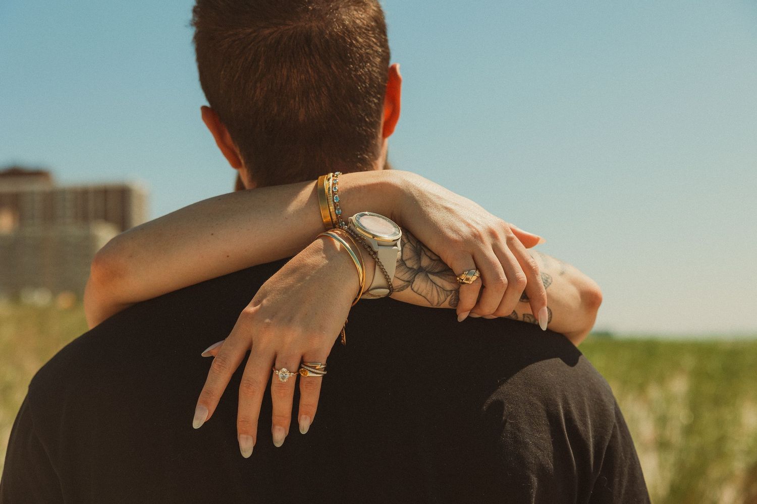 Intimate silhouettes embrace against golden sunlight in rustic outdoor setting at sunset.