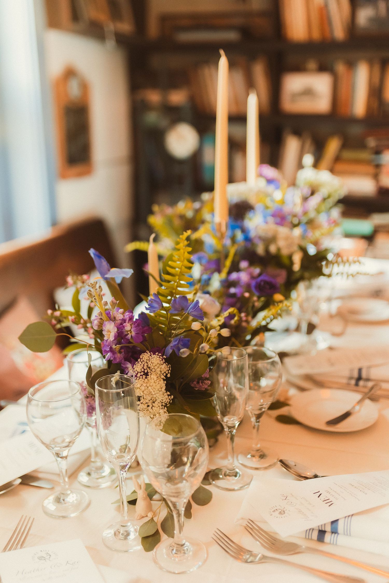 An elegant table setting with purple wildflowers and tall golden candles.