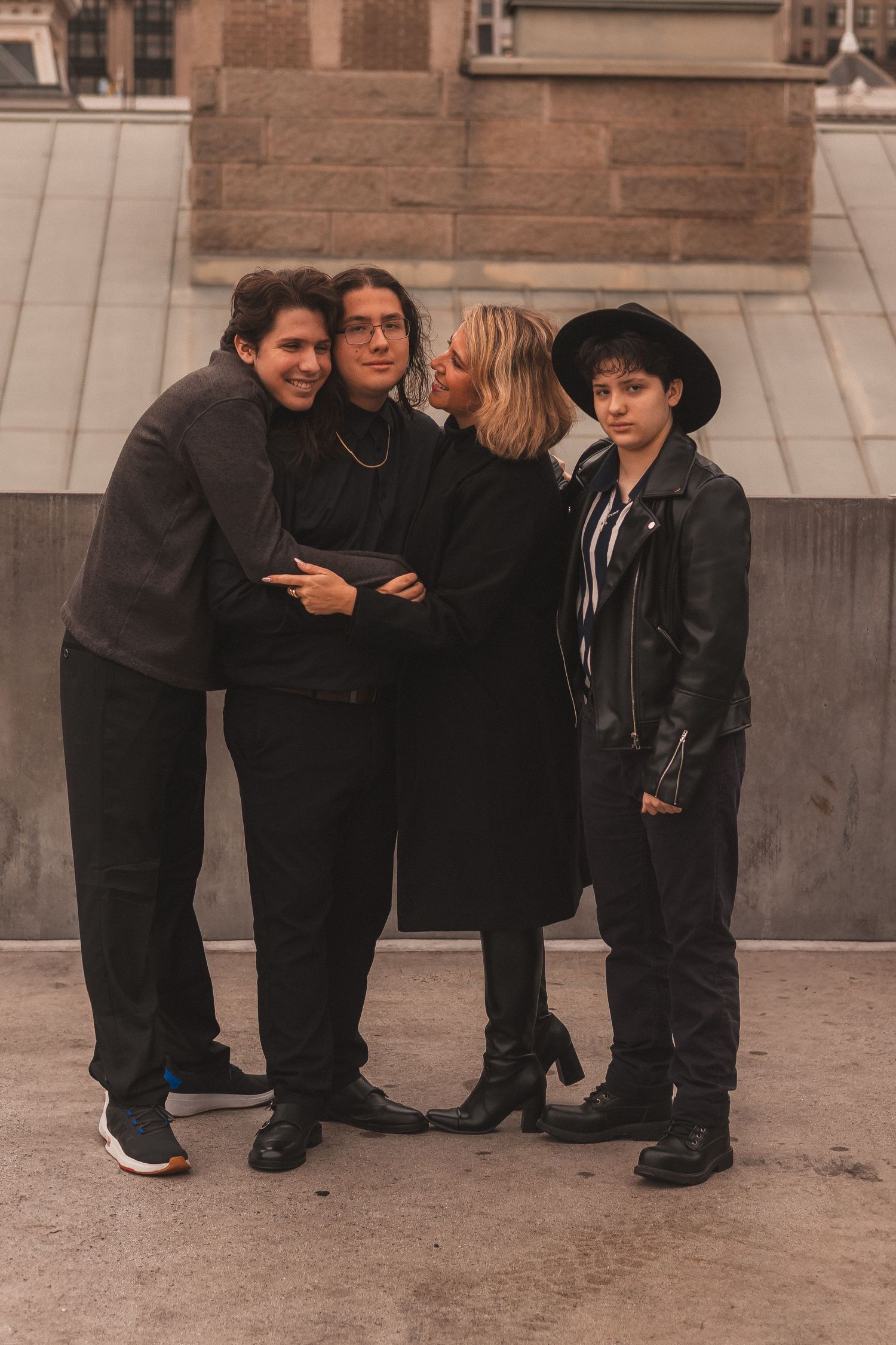 A group of four friends share a candid moment while posing on a city rooftop.