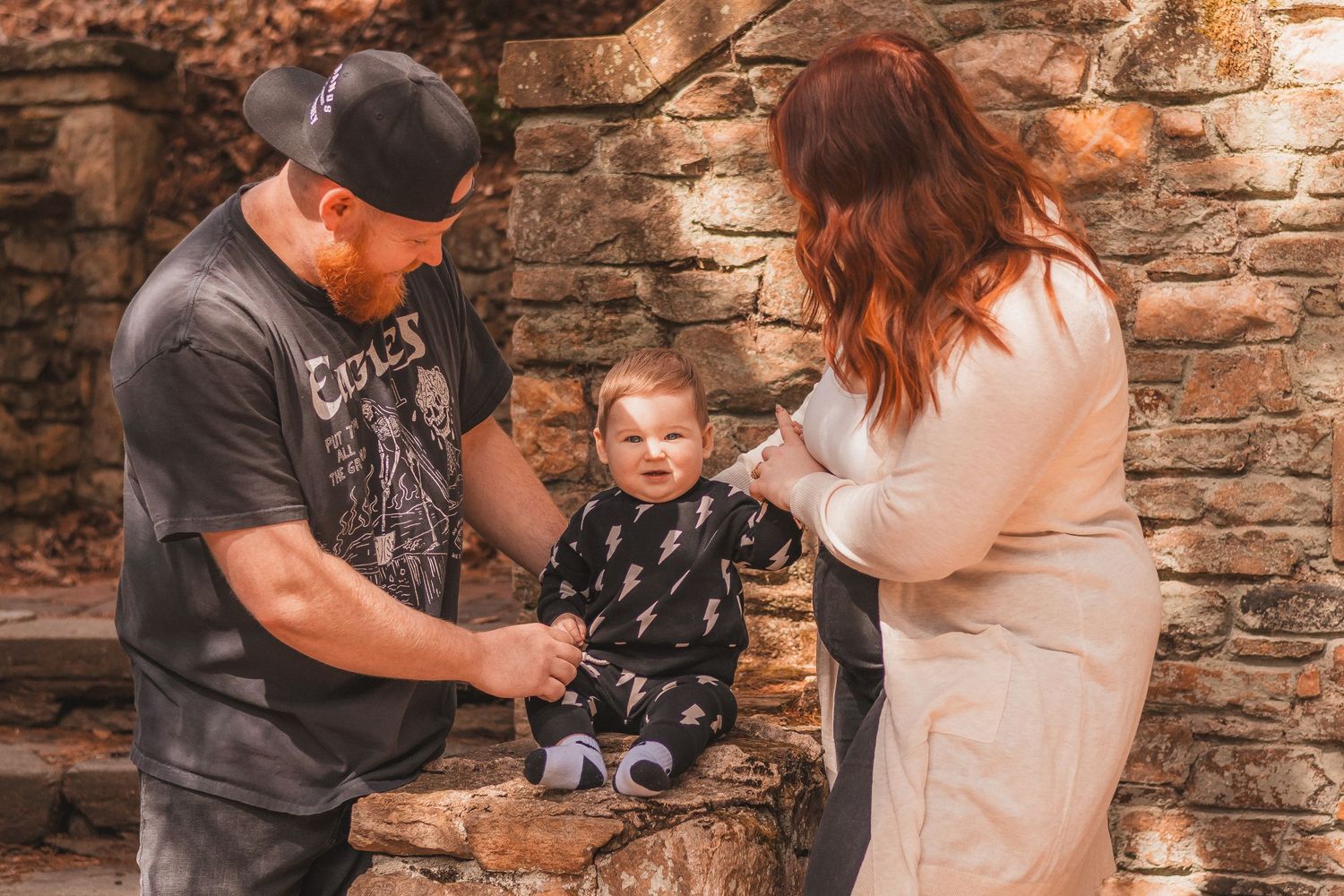 A family shares a playful moment together against a weathered stone wall.