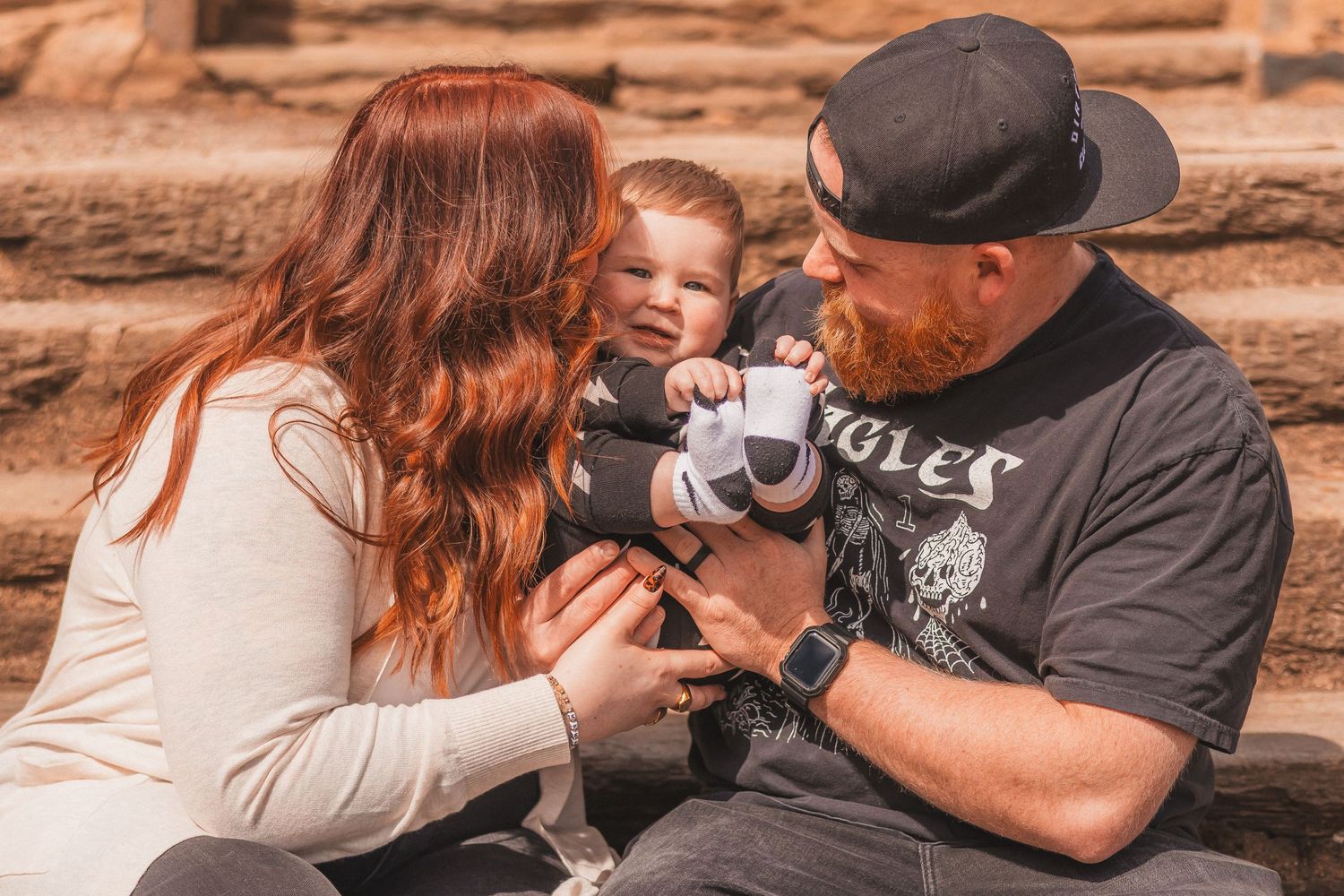 Family shares tender moment together on rustic stone steps.