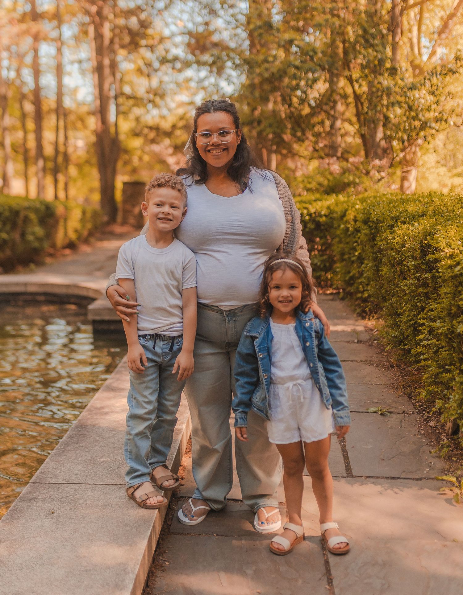 Family standing together on a pathway near water on a warm autumn day in golden sunlight.