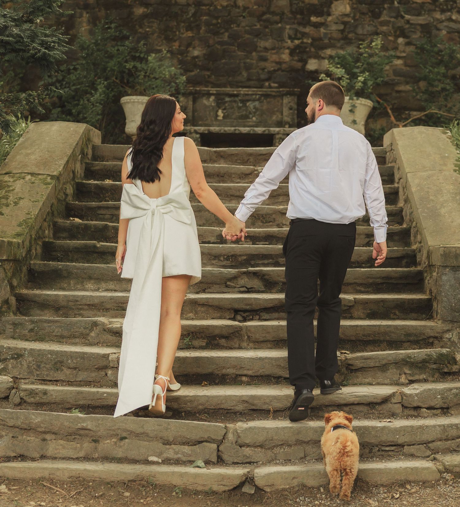 Couple holding hands walking up stone steps at a romantic outdoor location.