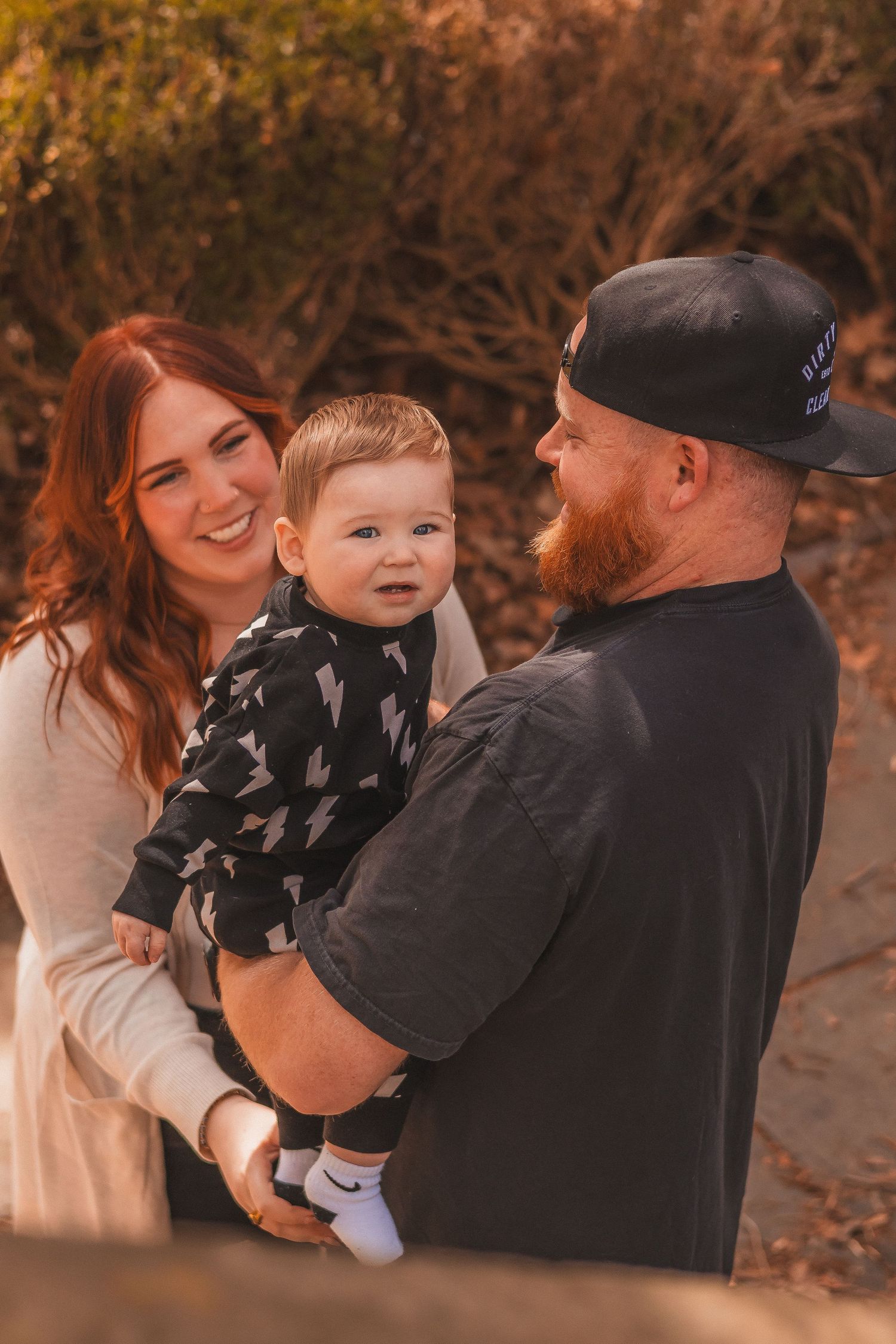 A family shares loving smiles together during an outdoor autumn photoshoot.