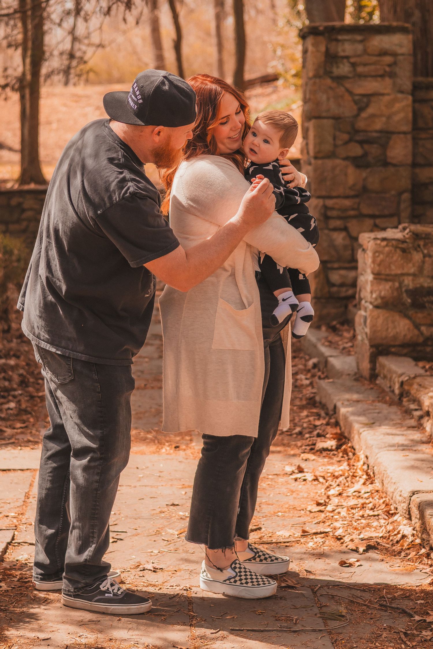Family embraces in tender moment on autumn path with stone architecture.