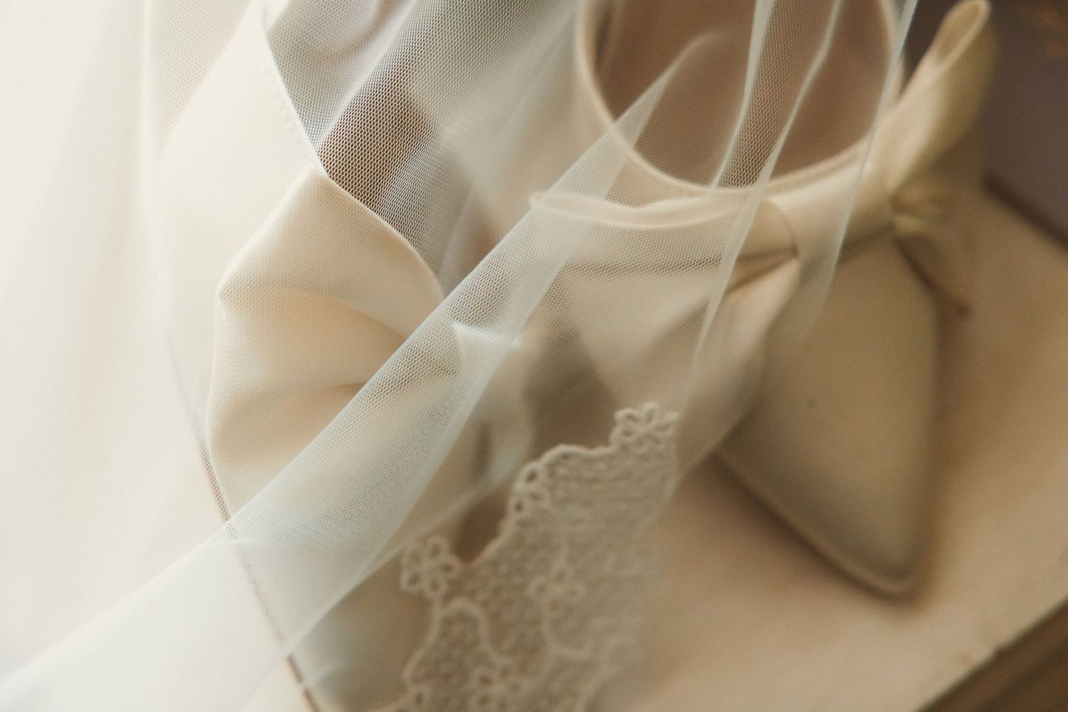 Close up detail of delicate lace trim and sheer fabric from a white wedding dress.