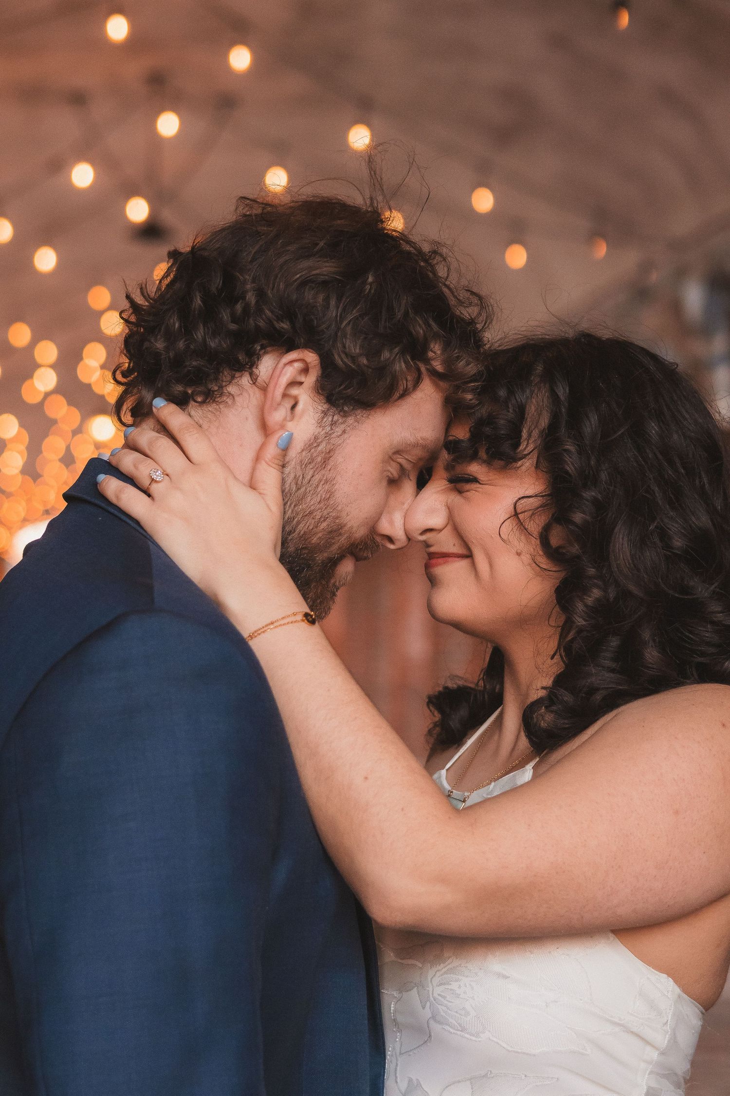 An intimate close-up of a couple sharing a tender moment under glowing lights.