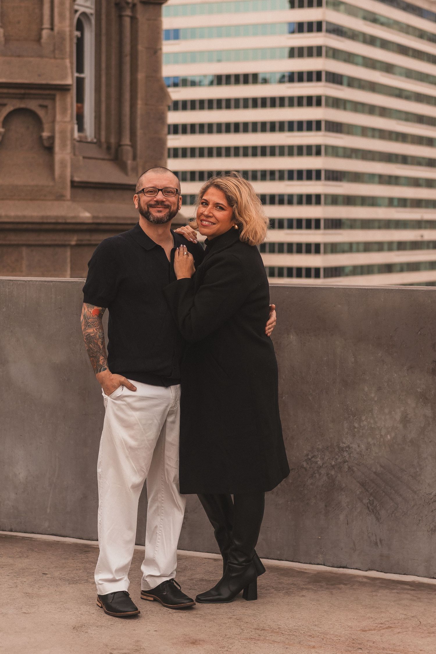 Romantic couple in contrasting black and white outfits posing together by historic architecture.