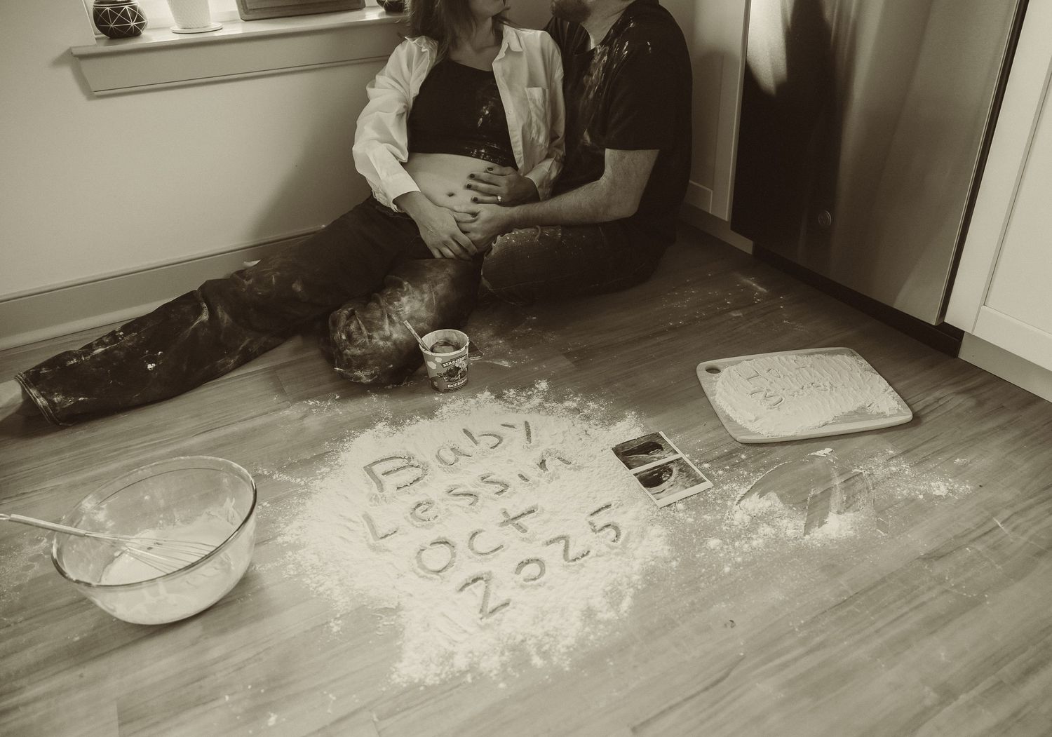 Sepia-toned panorama shows a person sitting cross-legged on floor writing on papers scattered along hardwood flooring.
