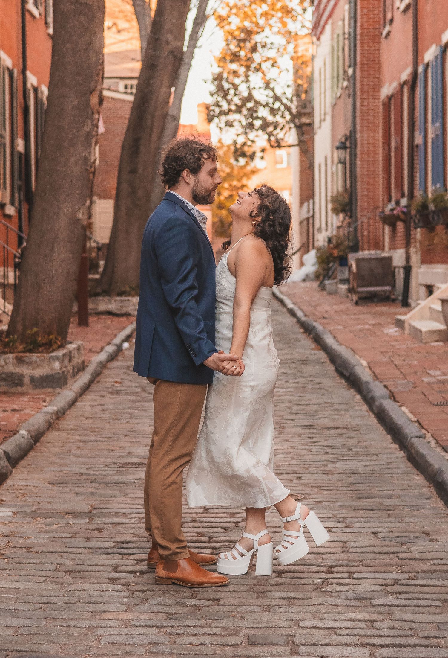 A couple shares a tender moment on a historic cobblestone street.